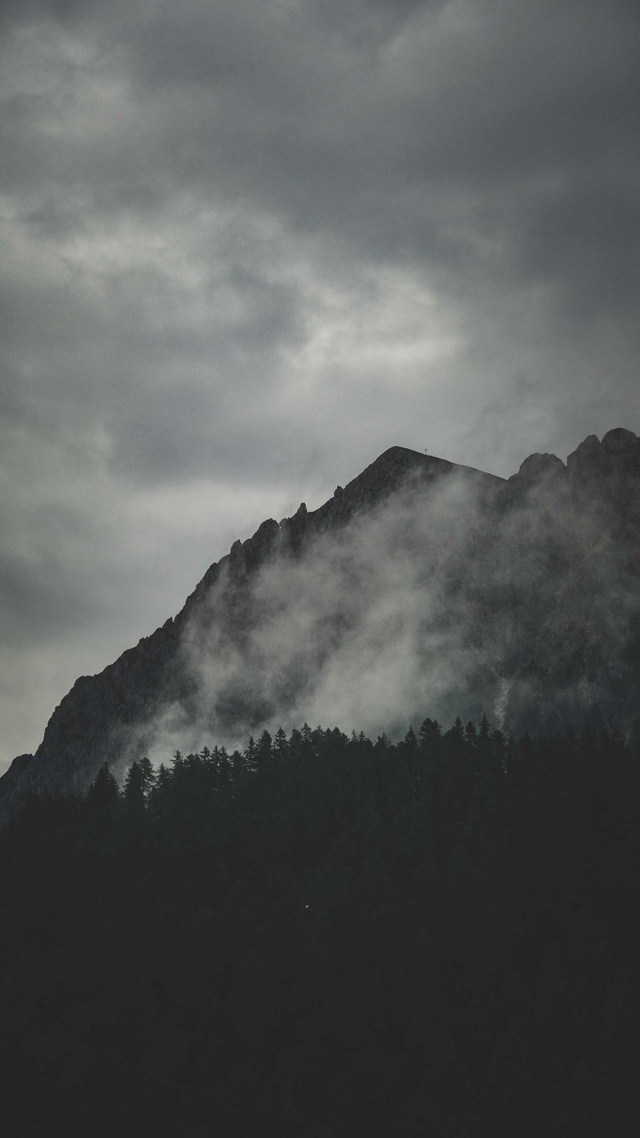 A summit cross on a misty mountain peak